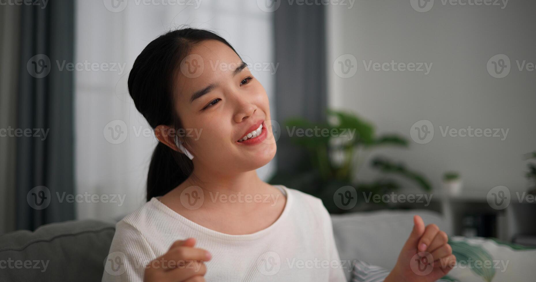 selectivo enfocar, relajado joven mujer vestir inalámbrico auriculares disfrutando descanso sentado en sofá en vivo habitación escuchando a música y bailando a hogar foto