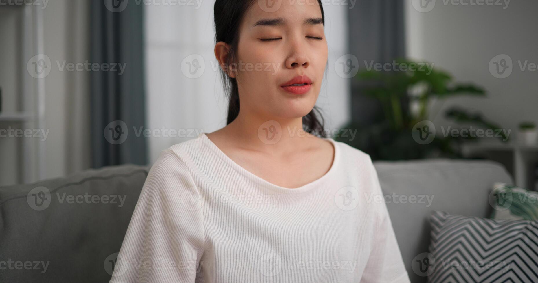 Selective focus, Young attractive woman sitting resting on sofa with eyes closed do meditation in the living room at home, deep relaxation practice, breathing fresh air photo