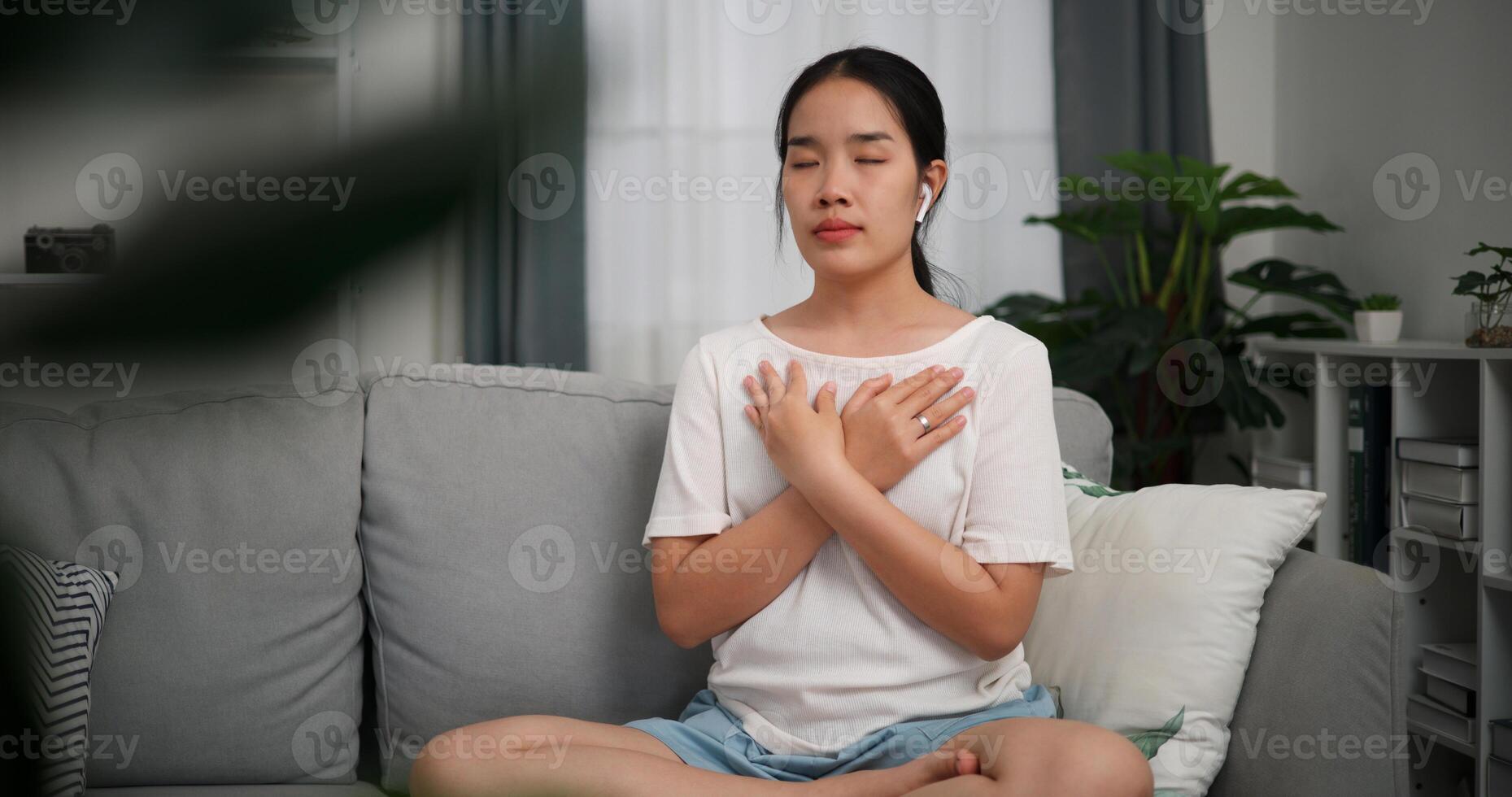 Selective focus, Relaxed young woman wear wireless headphones enjoying rest on sofa in living room, breathing fresh air with eyes closed, meditating at home photo