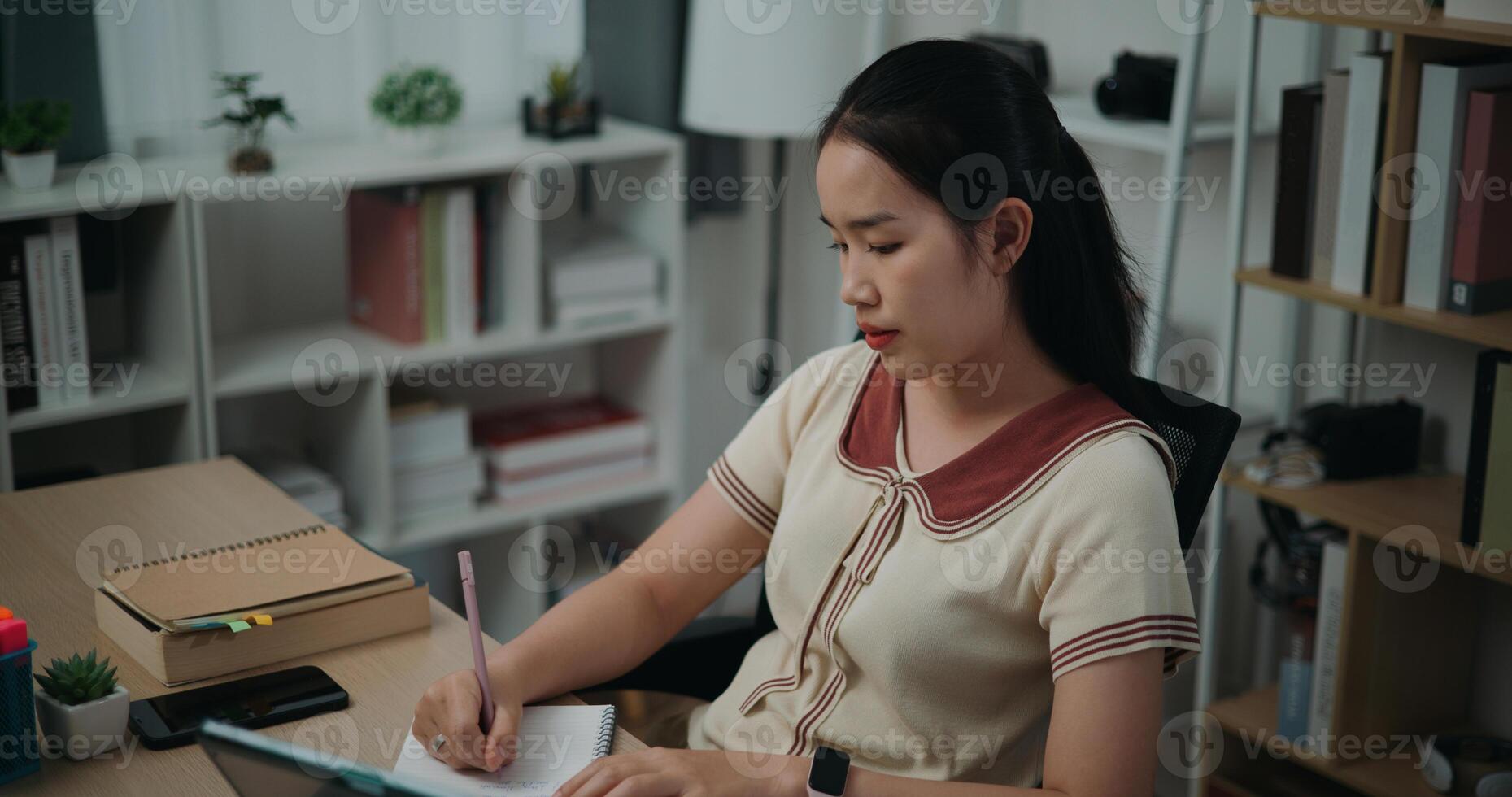 Selective focus, Side view,Female writer sitting at desk writing notes while working on tablet for online learning at home, creative thoughts to journaling, idea and inspiration photo