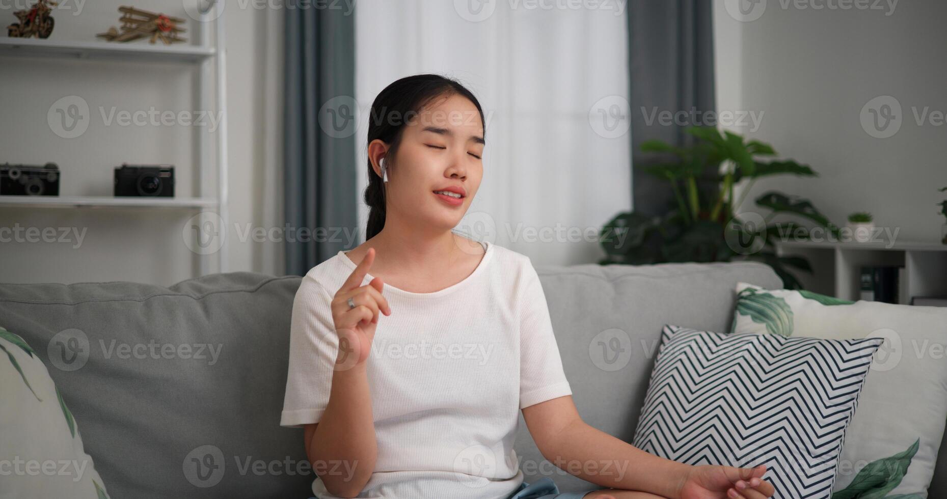 selectivo enfocar, relajado joven mujer vestir inalámbrico auriculares disfrutando descanso sentado en sofá en vivo habitación escuchando a música y bailando a hogar foto