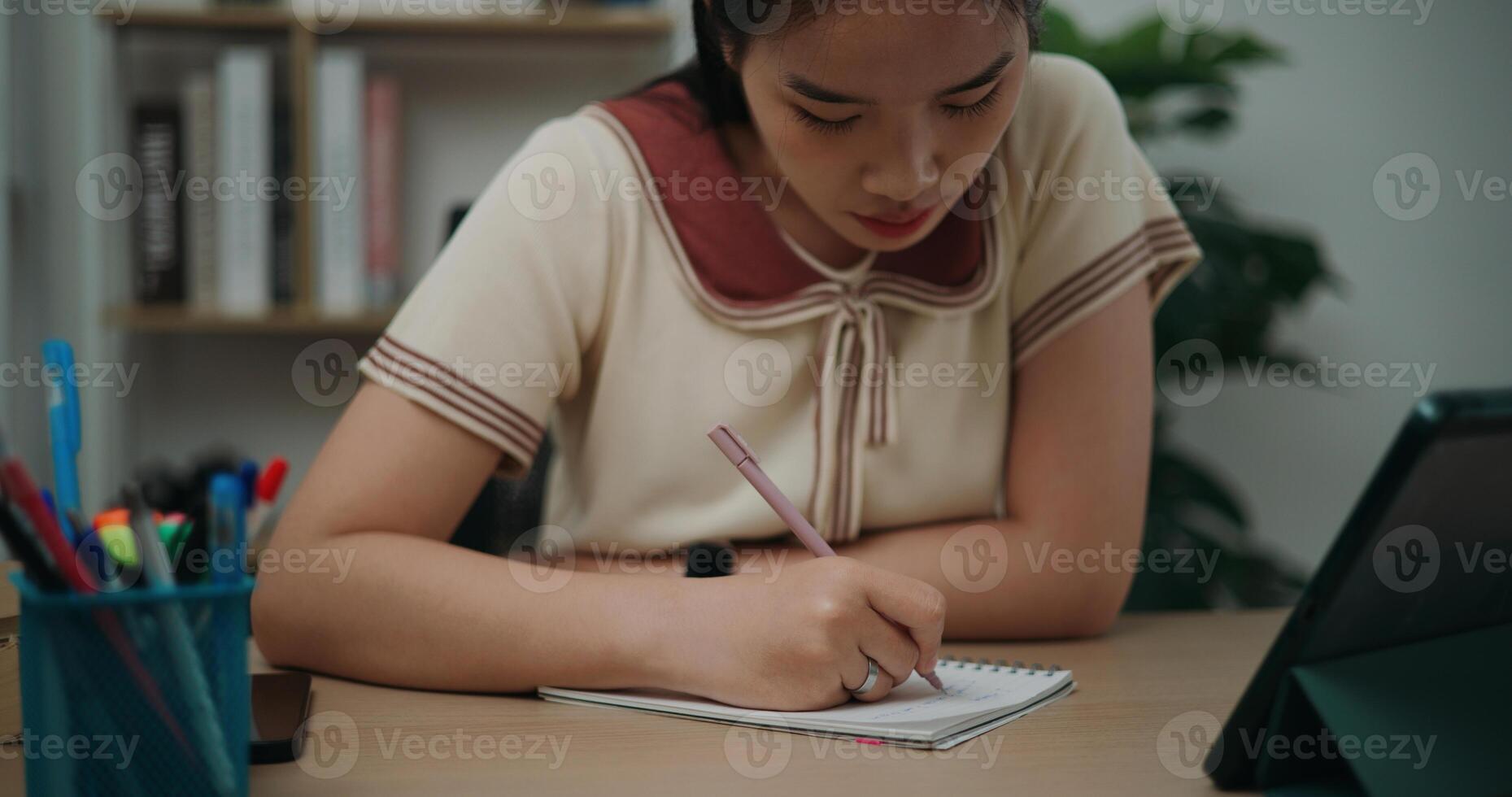 Selective focus, Front view,Female writer sitting at desk writing notes while working on tablet for online learning at home, creative thoughts to journaling, idea and inspiration photo