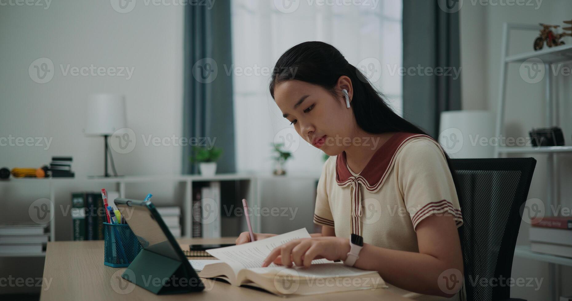 Selective focus, Side view, Female wireless headphones writer sitting at desk writing information on diary notebook while reading book at home, creative thoughts to journaling, idea and inspiration photo