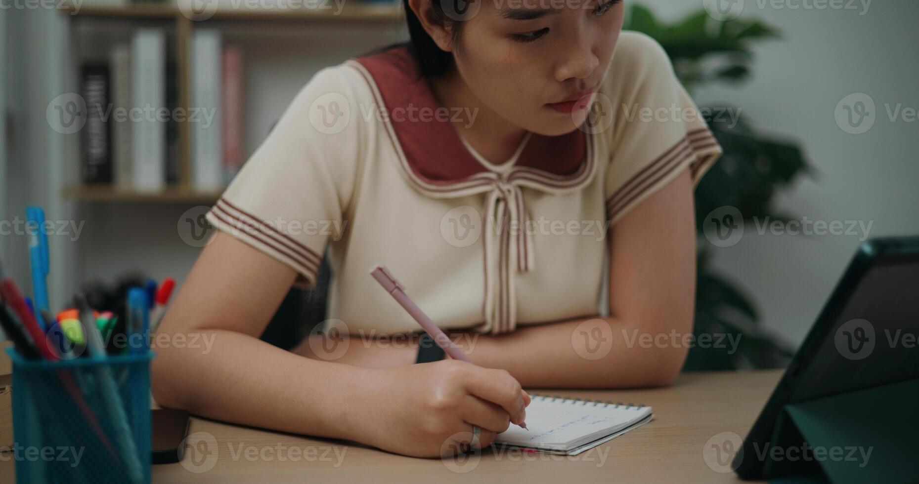 Selective focus, Front view,Female writer sitting at desk writing notes while working on tablet for online learning at home, creative thoughts to journaling, idea and inspiration photo