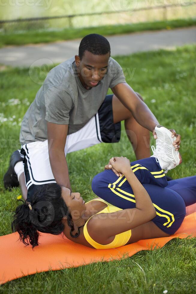 Black Woman Stretching On Orange Pad With Man photo