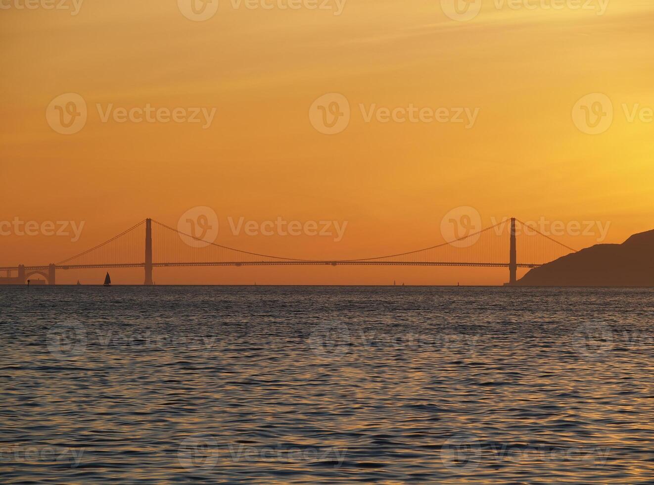 distante ver de dorado portón puente con naranja puesta de sol cielo foto