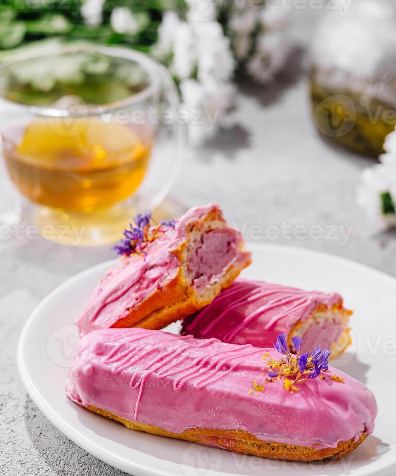 Eclairs with pink glaze and tea photo