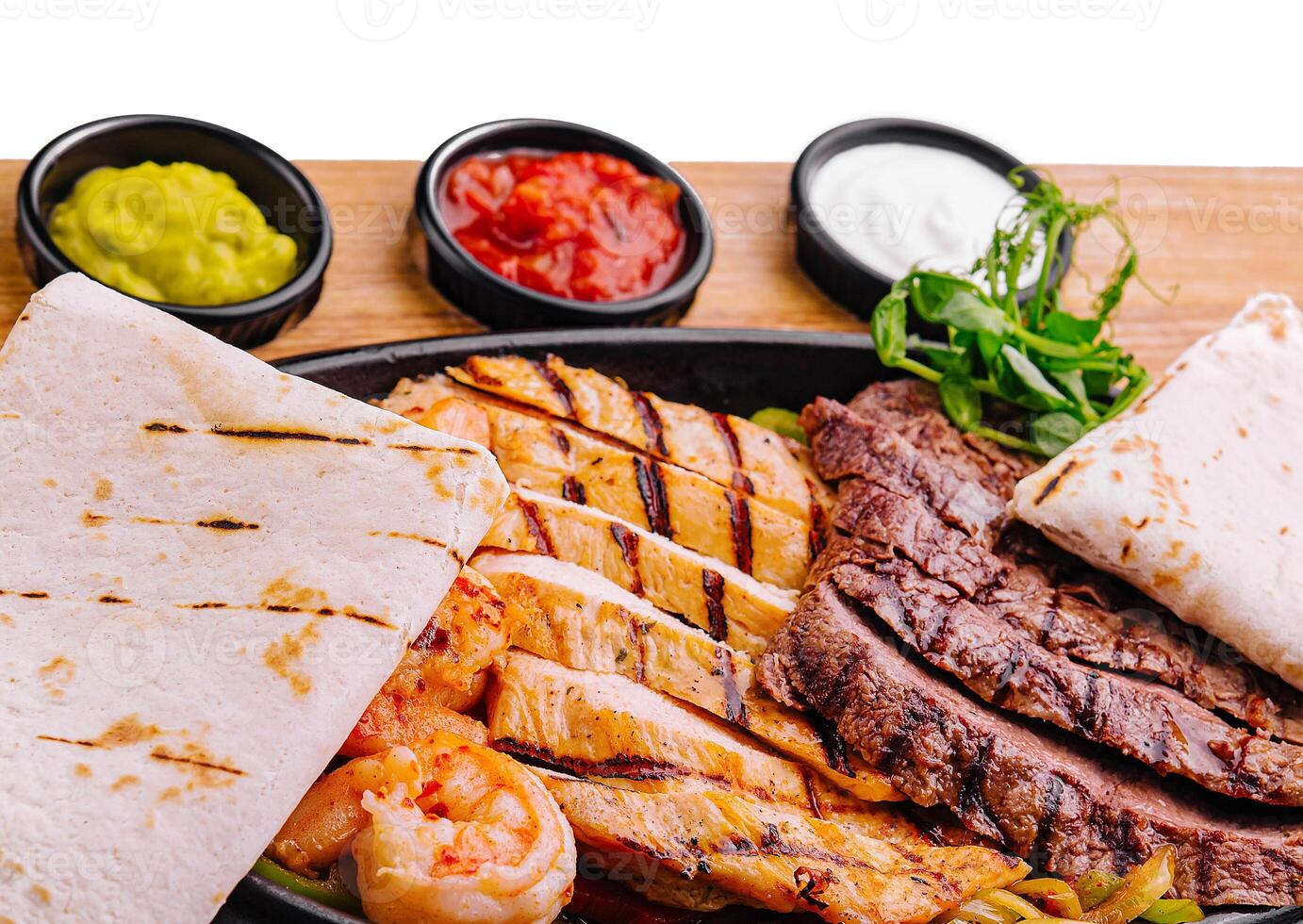 Beef chicken and shrimp fajitas on a iron cast sizzling plate photo