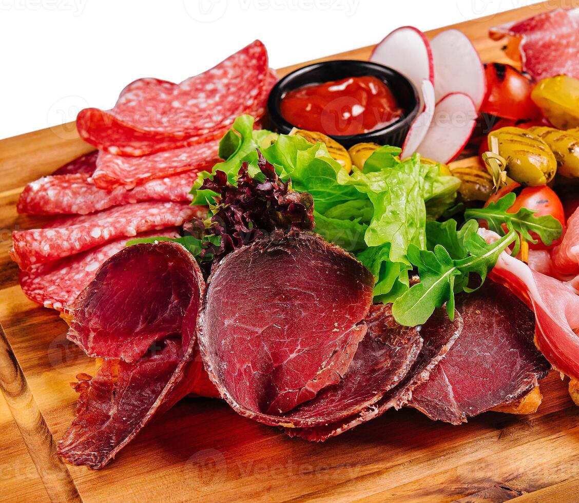 Variety of meats, sausages, salami, ham, olives, laid out on a wooden board photo