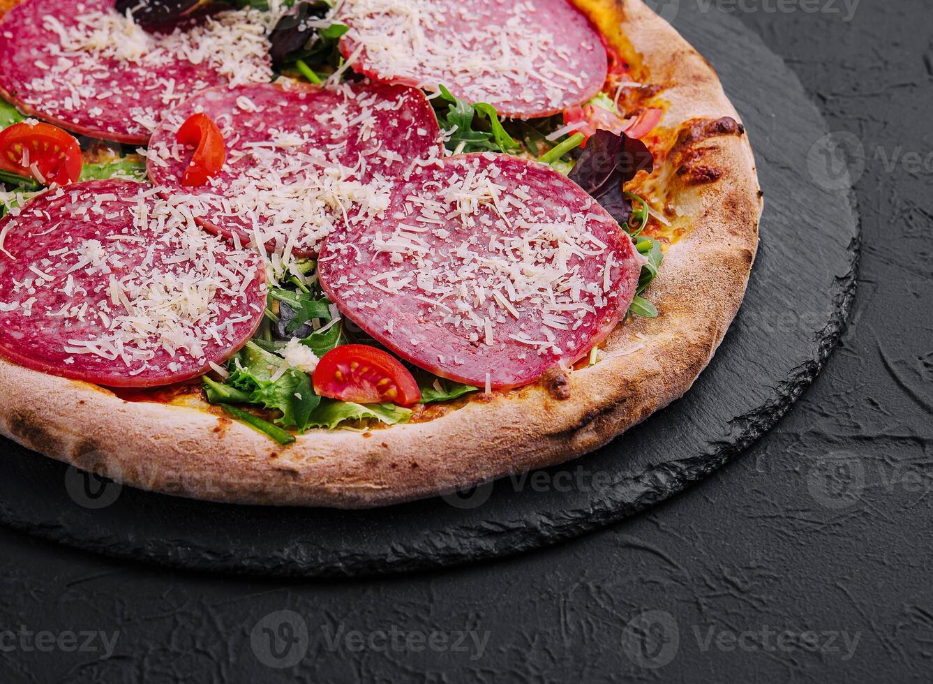 Delicious pizza with salami, arugula and tomatoes photo