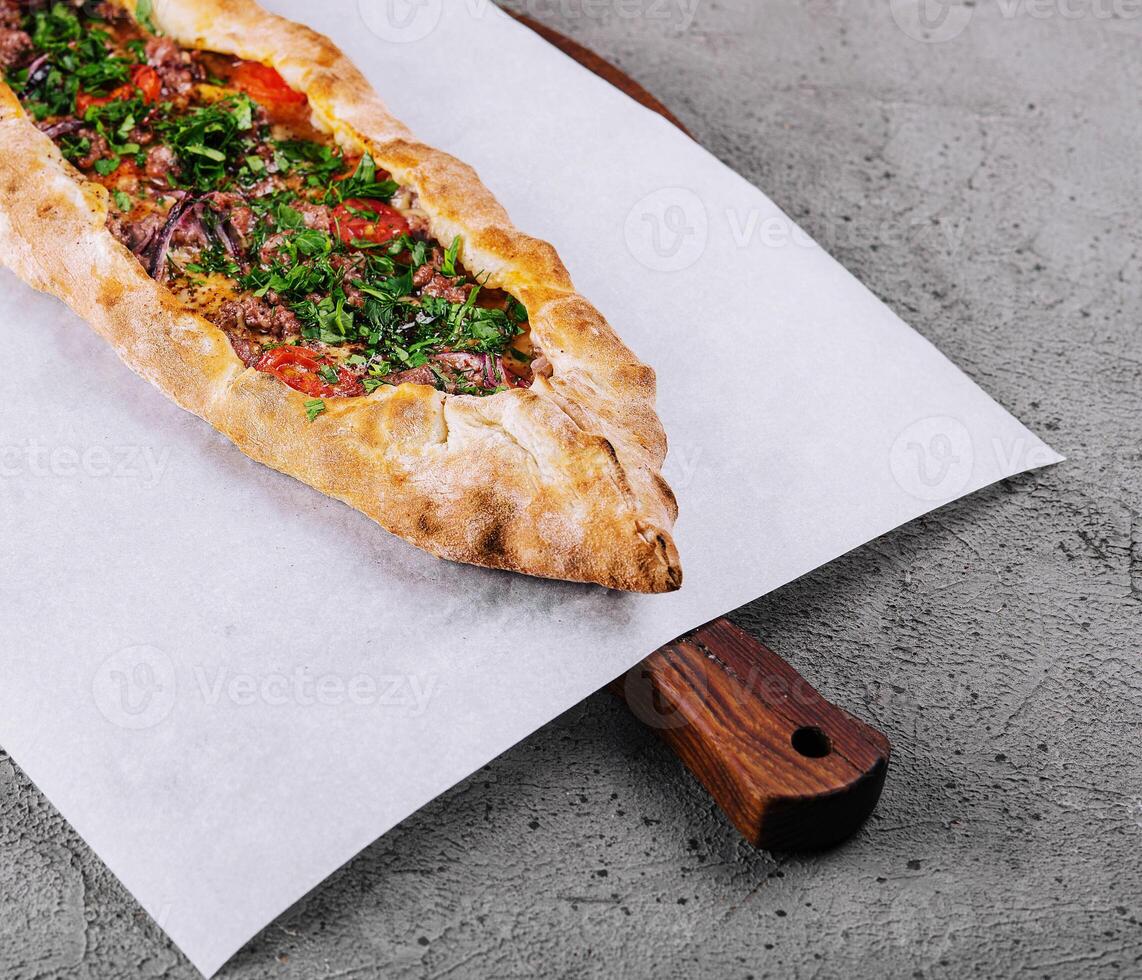 traditional turkish meat pide on wooden board photo