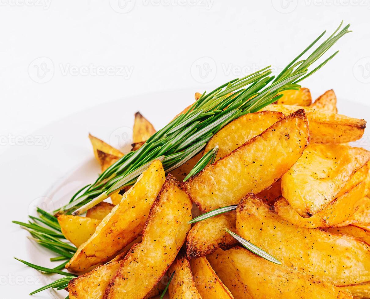 Baked potato wedges with rosemary on plate photo