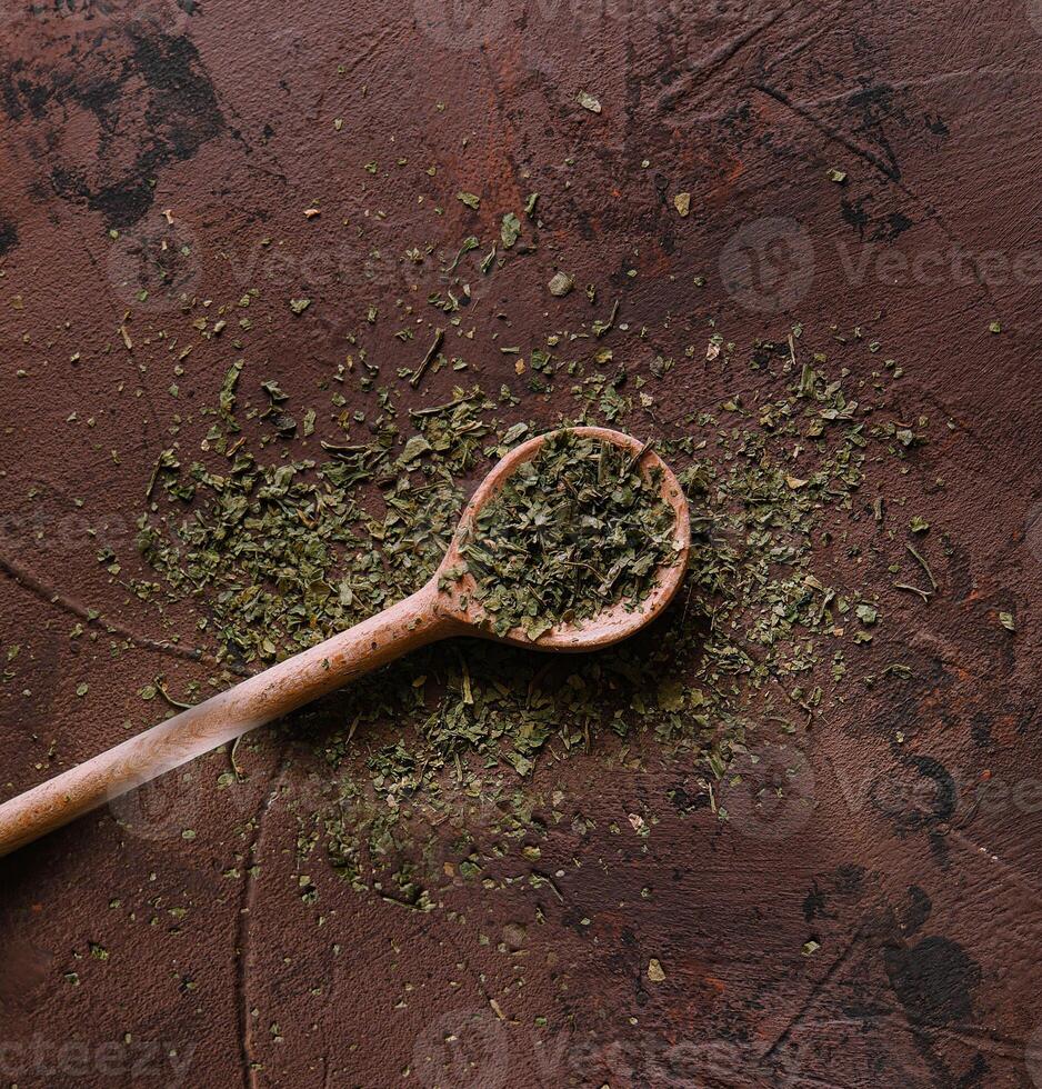 A pile of a green spice mix dried vegetables and herbs on wooden spoon photo