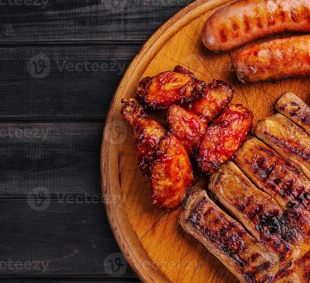 pork ribs with chicken and sausages on wooden board photo