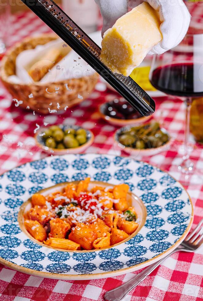 hef grates cheese to the plate with fresh penne pasta photo