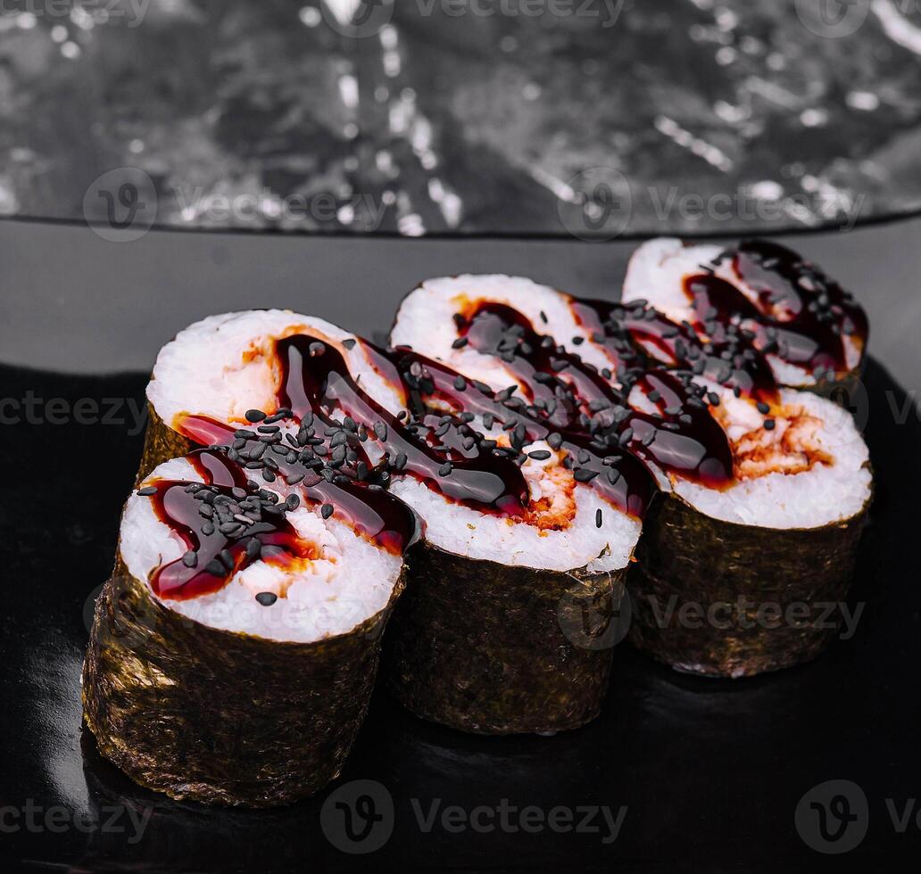 sushi roll maki with eel and unagi sauce on a black plate photo