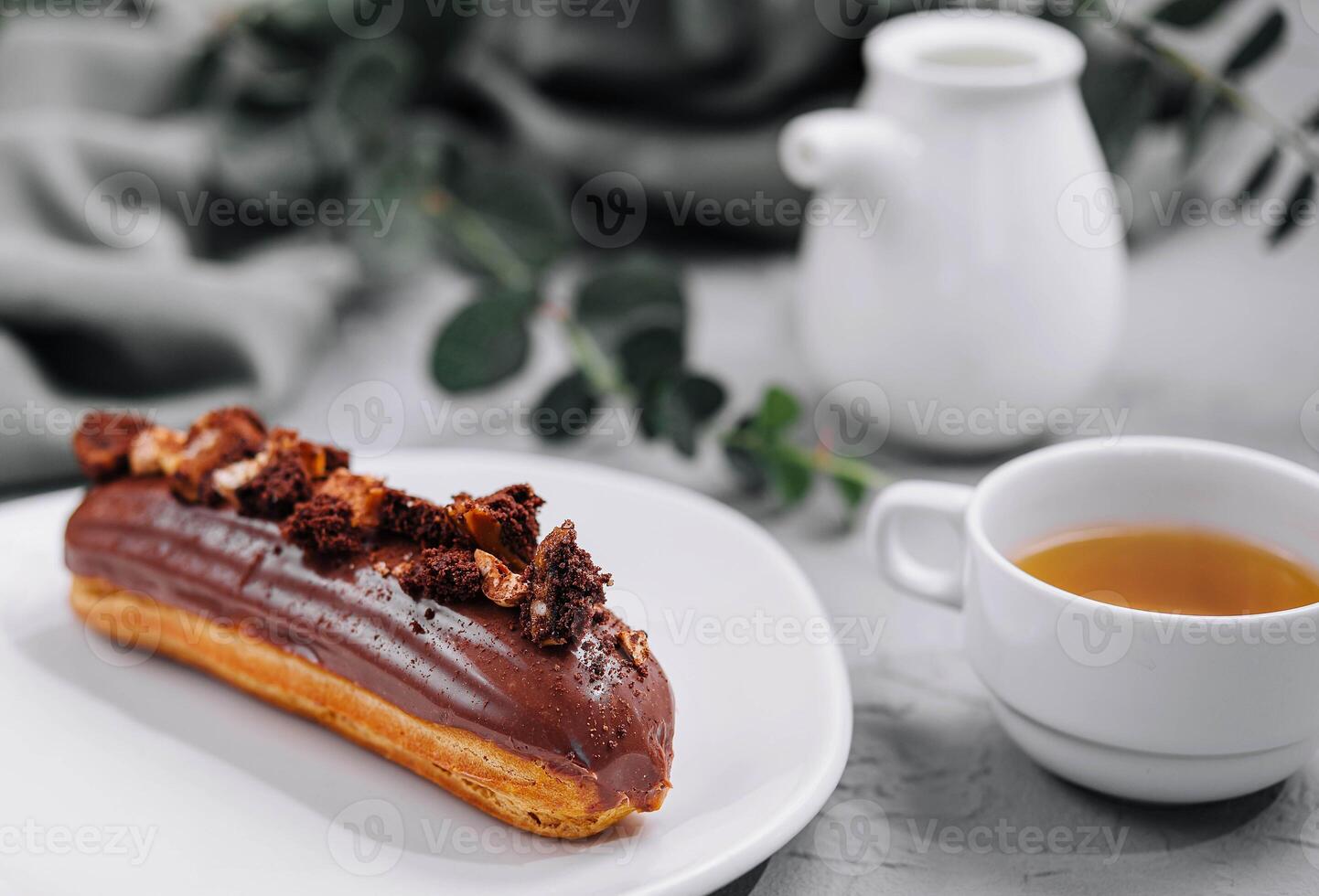 Eclair with Chocolate Cream and Hazelnuts and tea photo