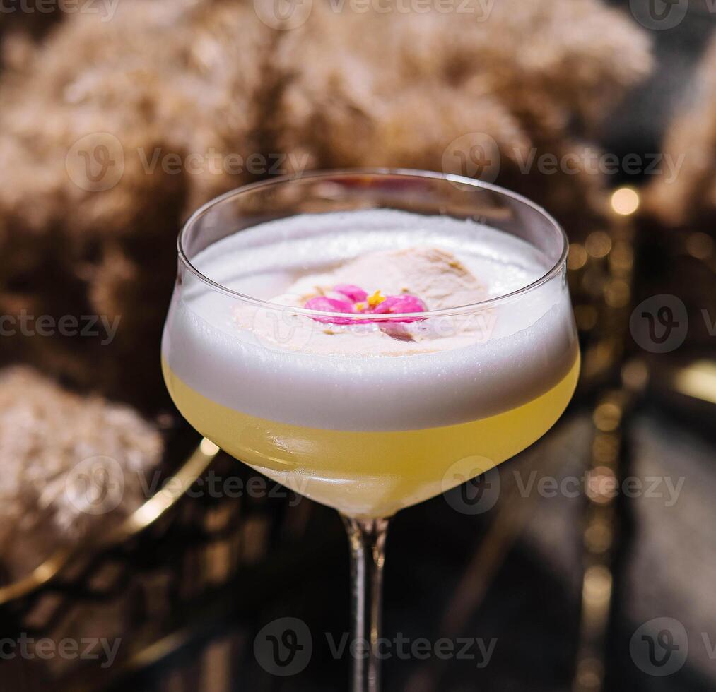 Glass with yellow lemon cocktail with foam photo