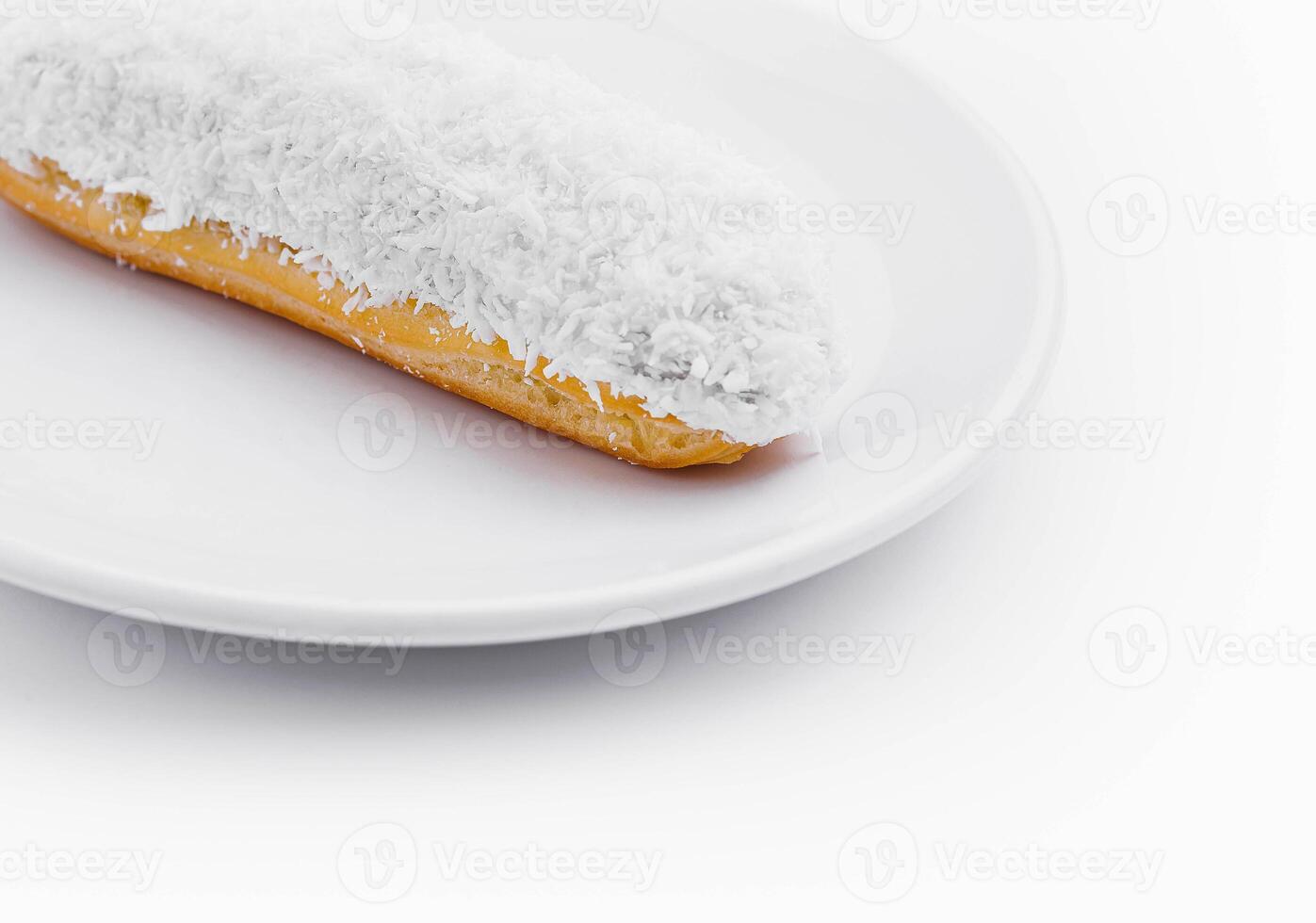 eclair in white glaze and coconut flakes photo