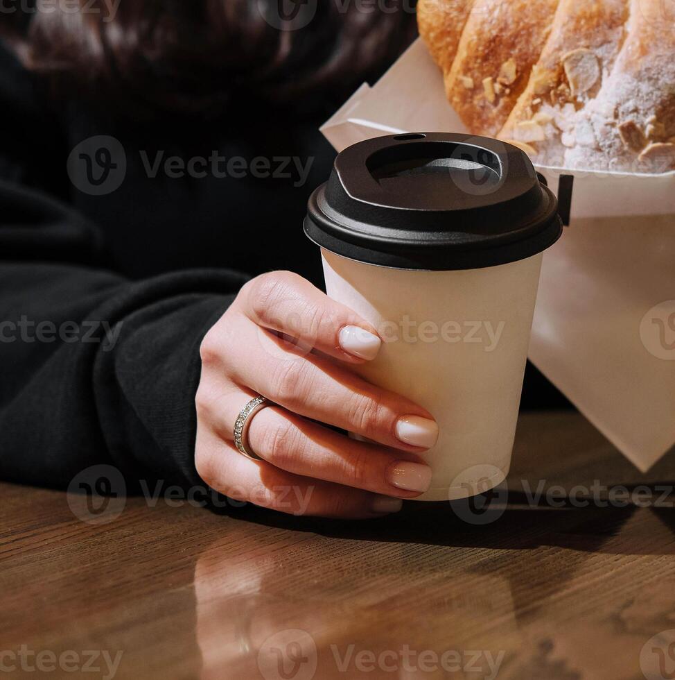 Woman holding a mug of coffee and a croissant photo