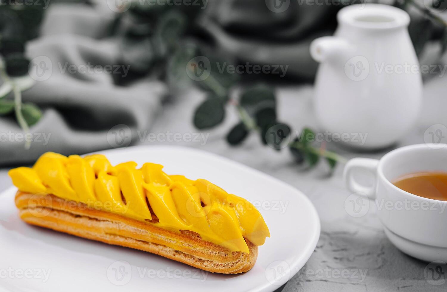 Fresh tasty eclair on white plate and cup of tea photo