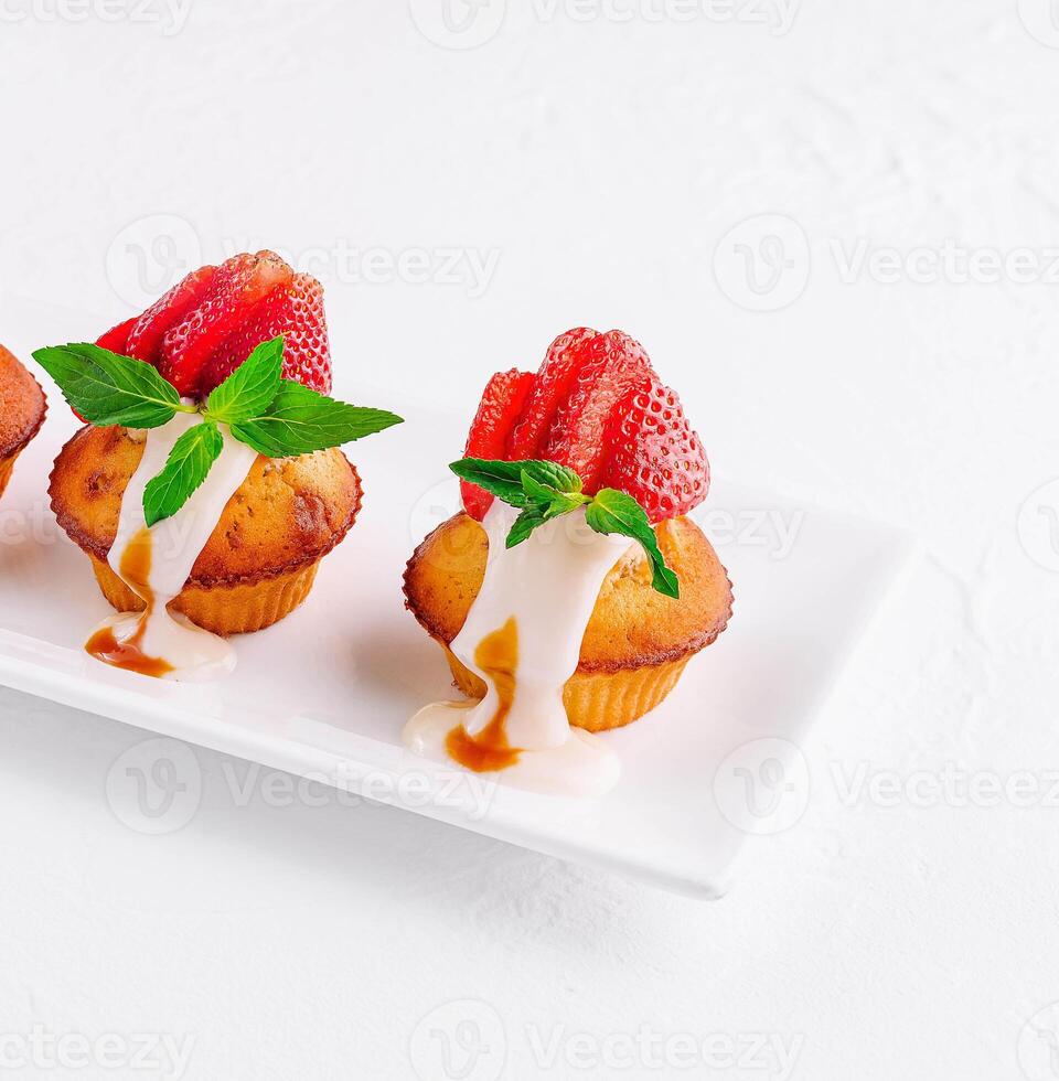 Vanilla cupcakes with strawberry on white plate photo