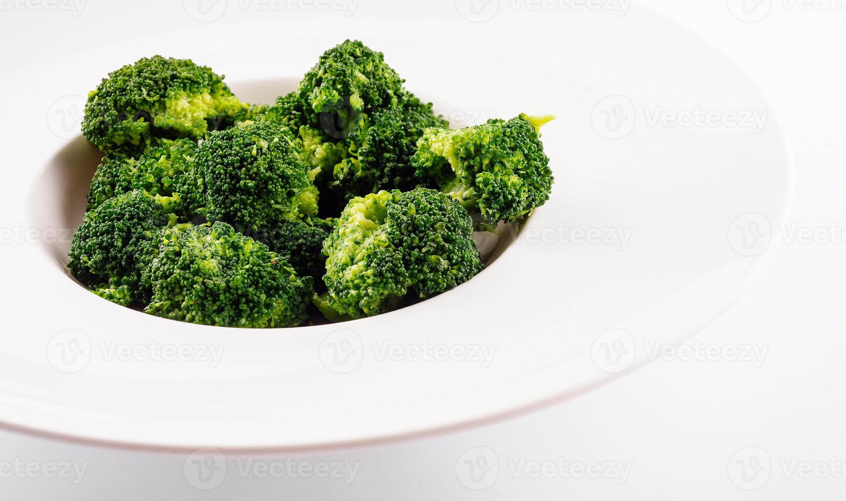 Fresh green broccoli in white circle plate isolated on white photo