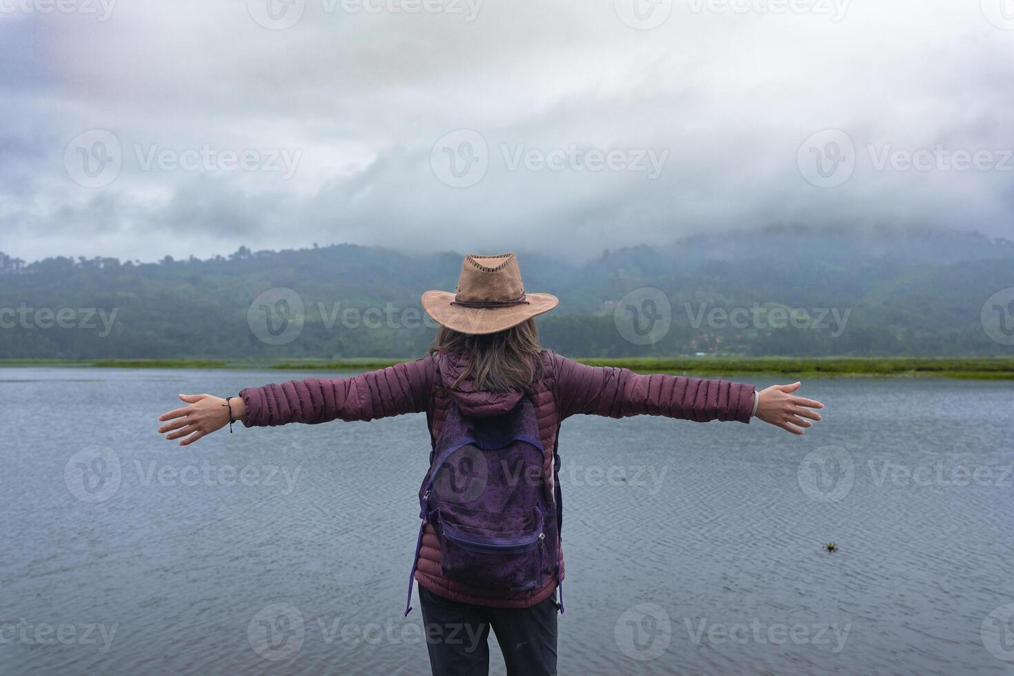 Traveler woman opens her arms in front of a lagoon as a sign of relaxation in Peru. photo