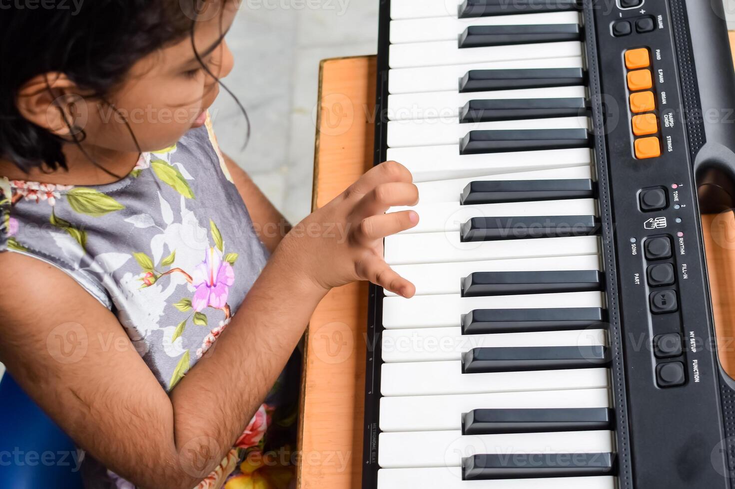 Asian cute girl playing the synthesizer or piano. Cute little kid learning how to play piano. Child's hands on the keyboard indoor. photo