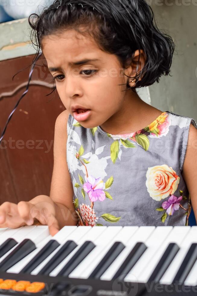 Asian cute girl playing the synthesizer or piano. Cute little kid learning how to play piano. Child's hands on the keyboard indoor. photo