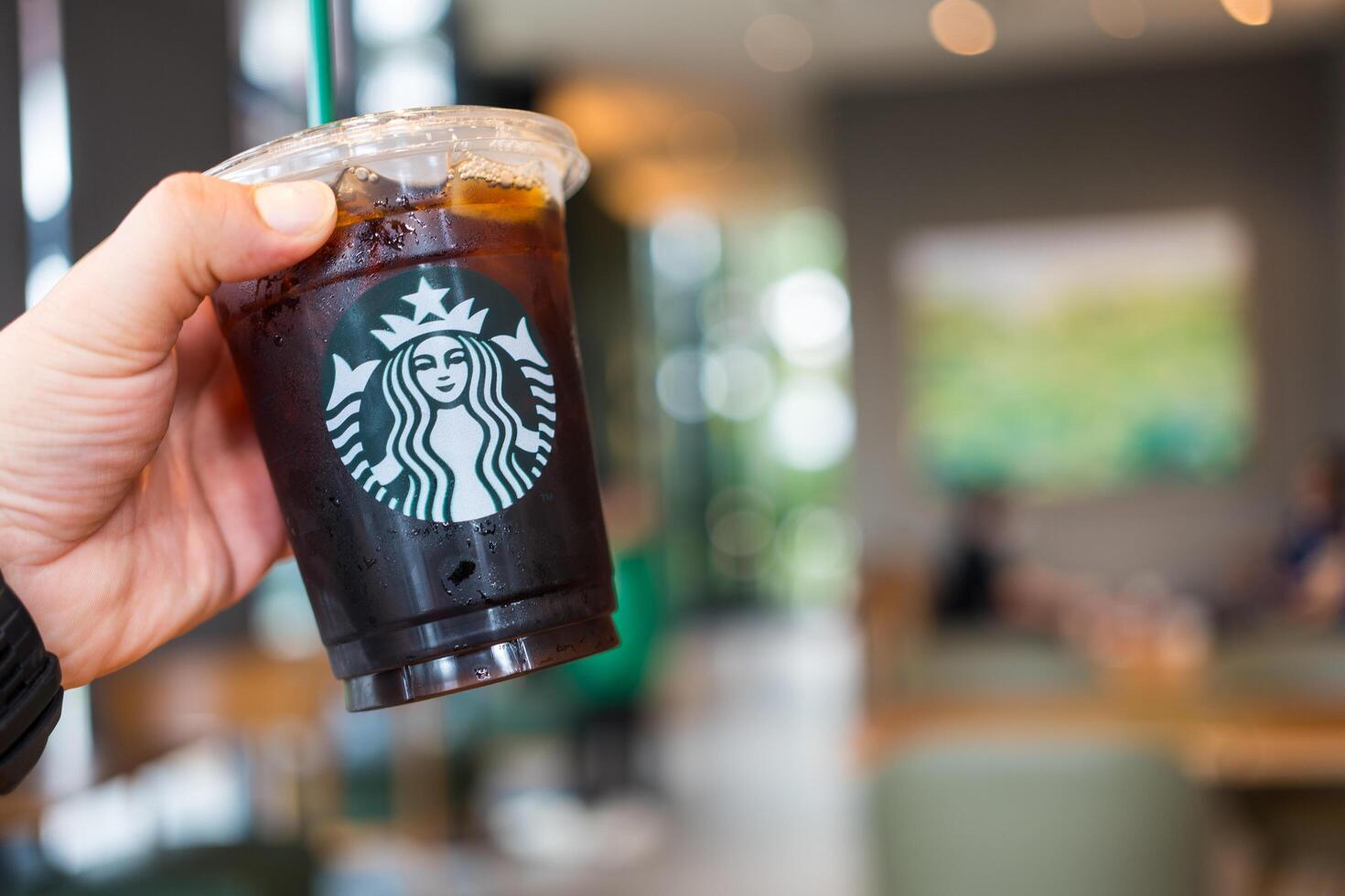 Bangkok, Thailand - February 29, 2024 Man holding a Starbucks cold brew beverage cup in hand. photo