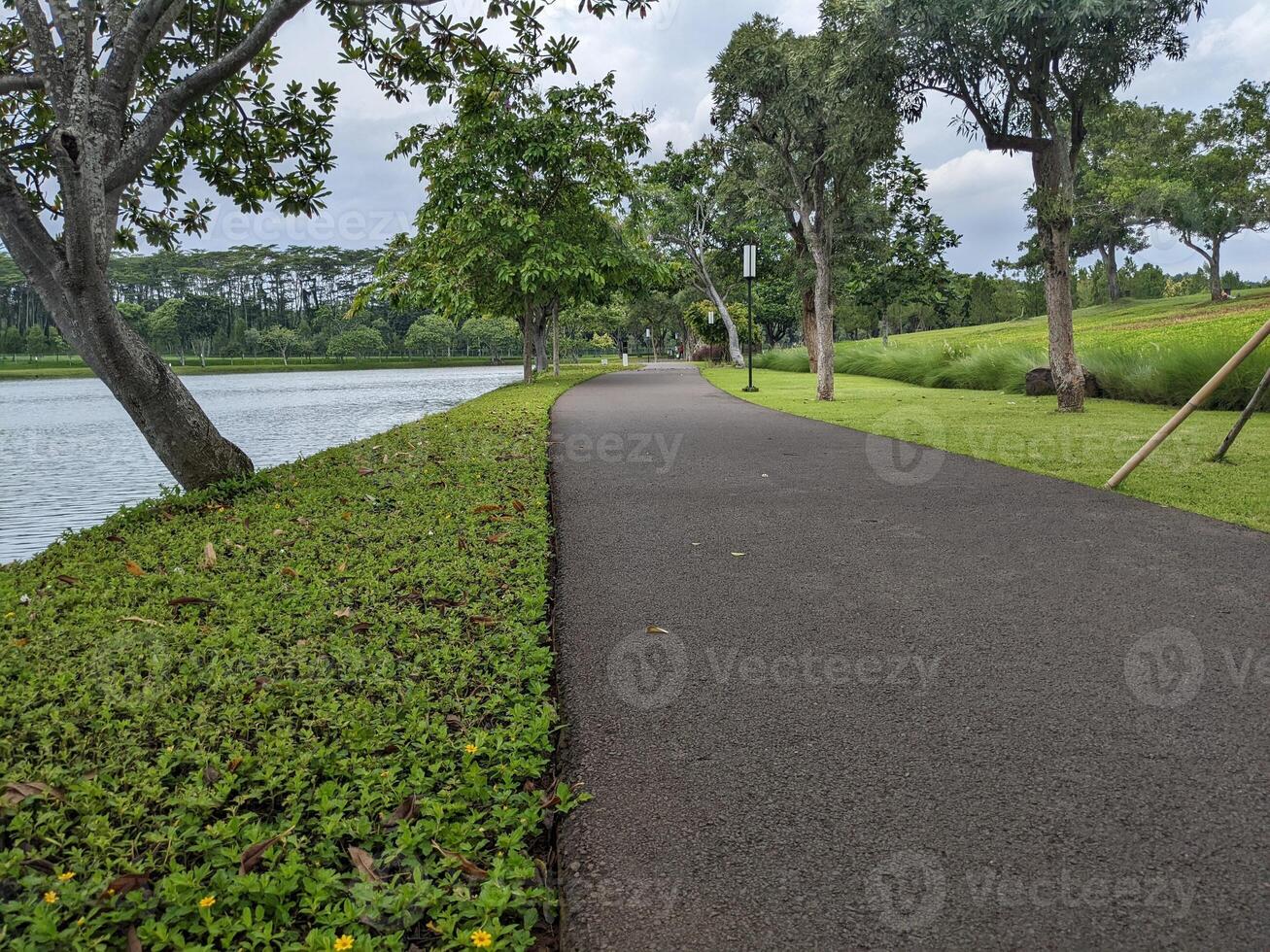 Mini jogging park on the Semarang Central Java with lake, cloudy vibes and blue sky. The photo is suitable for park background, relax and enjoy place content media.