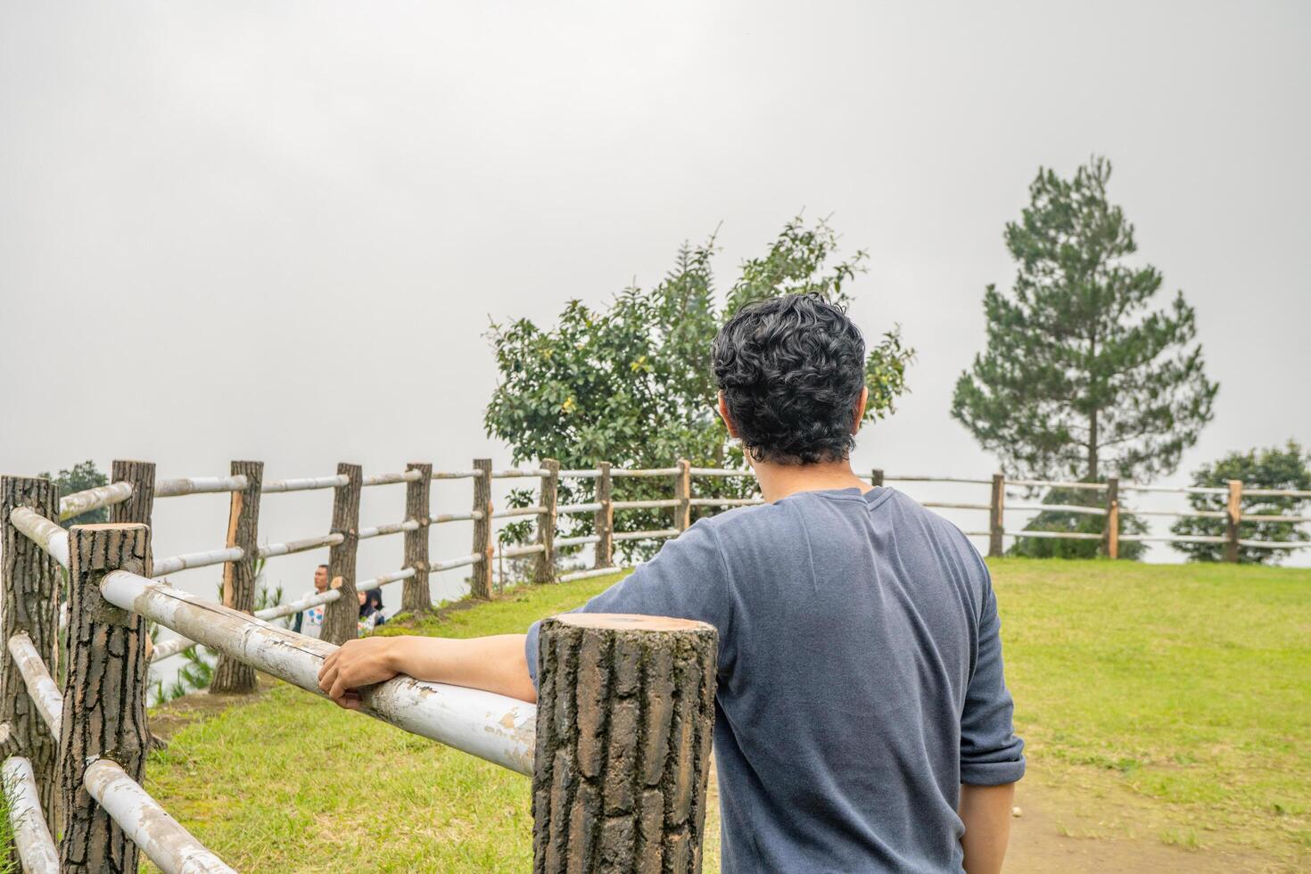 Young man stand on the grass field horse arena. The photo is suitable to use for calm enjoyed activity, leisure activity and park background.