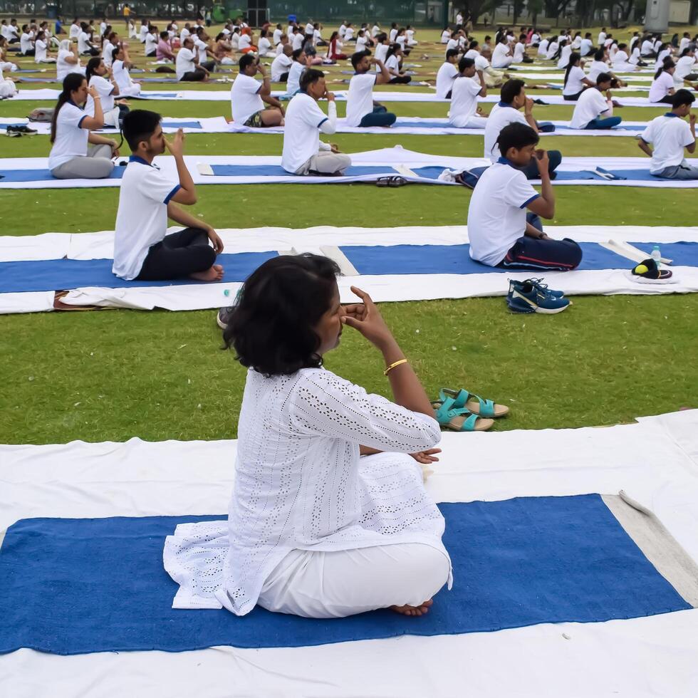 New Delhi, India, June 21, 2023 - Group Yoga exercise session for people at Yamuna Sports Complex in Delhi on International Yoga Day, Big group of adults attending yoga class in cricket stadium photo