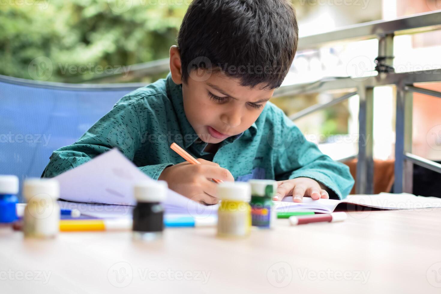 inteligente indio pequeño chico realizar pulgar pintura con diferente vistoso agua color equipo durante el verano vacaciones, linda indio niño haciendo vistoso pulgar pintura dibujo en de madera mesa foto