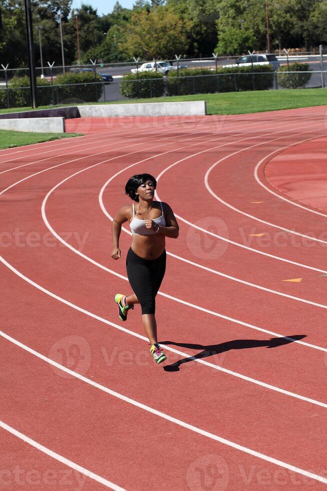Plump young black woman running on track photo