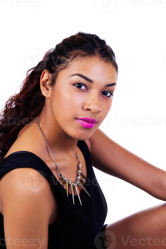 Attractive Latina Woman Sitting In Black Dress Looking At Camera photo