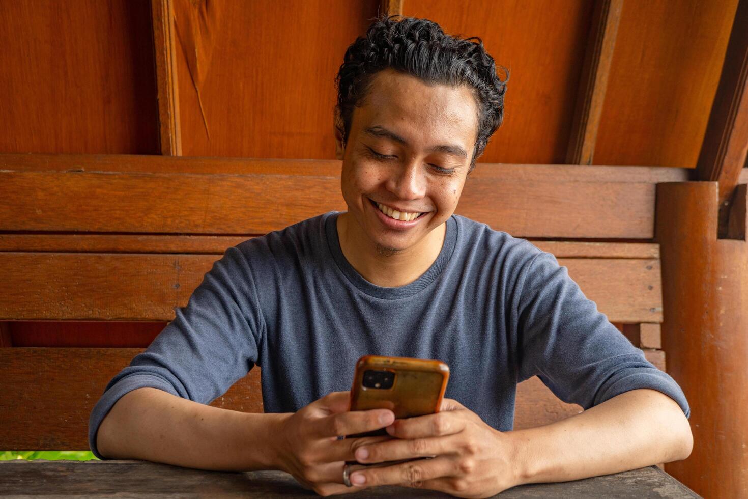 Man smile happy and surprised when looking at phone on the restaurant. The photo is suitable to use for expression advertising and ecommerce.
