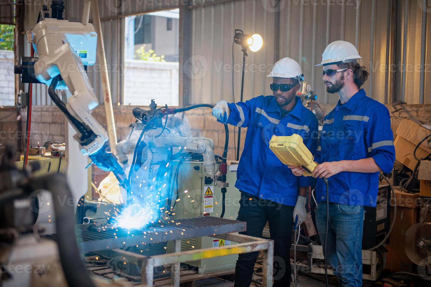 Two engineers mechanic using computer controller Robotic arm for welding steel in steel factory workshop. Industry robot programming software for automated manufacturing technology . photo