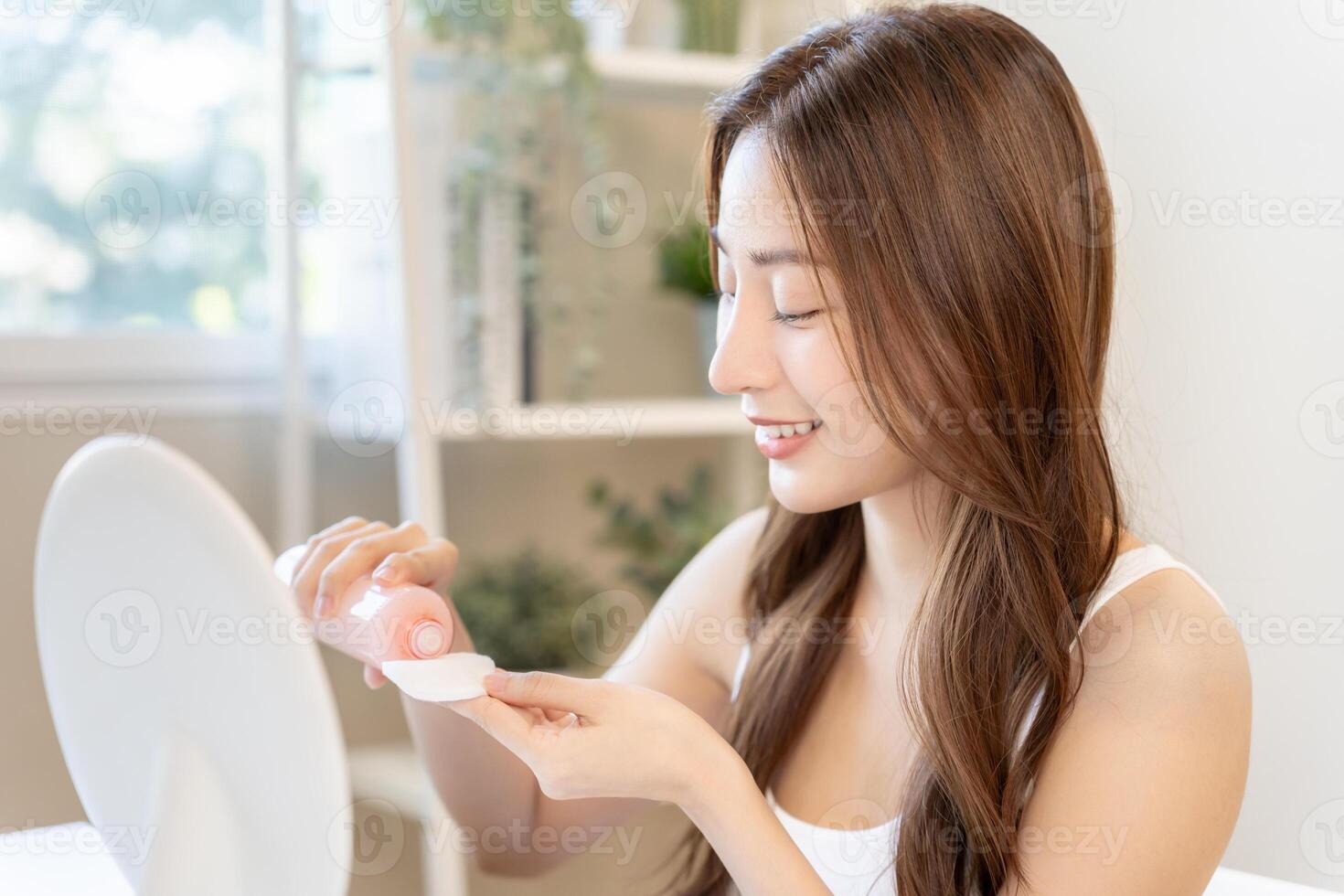 Beautiful Asian woman sit in front of a mirror and smile use cleaning . face of healthy woman apply makeup. Advertisement, lifestyle , cosmetics, makeup accessories, beauty activity, beautician photo