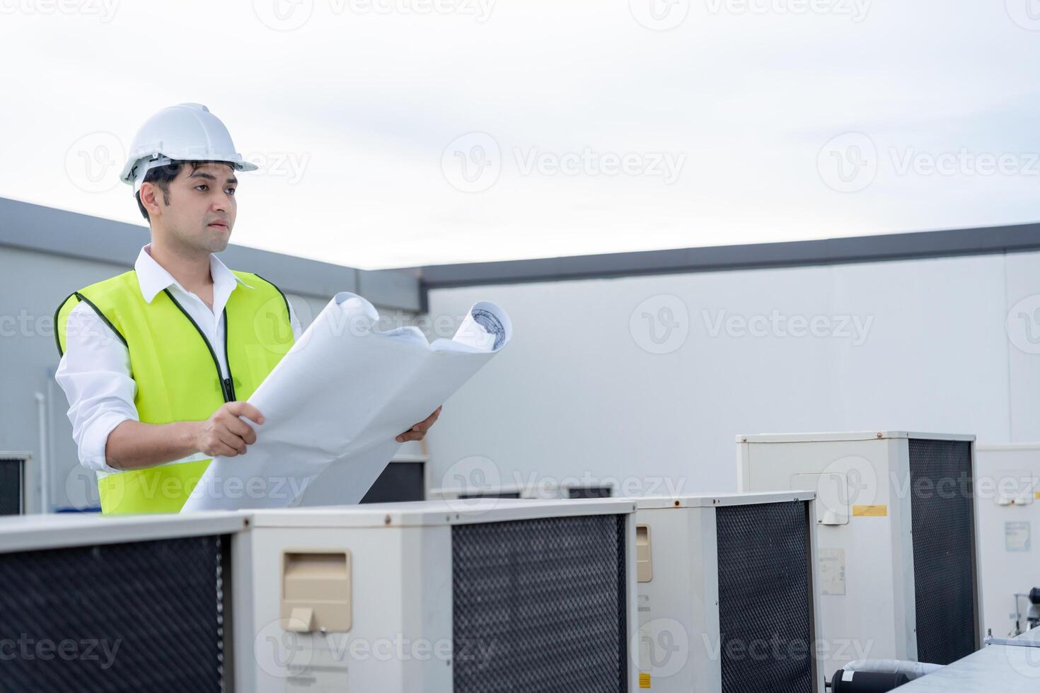 Asian maintenance engineer works on the roof of factory. contractor inspect compressor system and plans installation of air condition systems in construction. Blueprint, inspector, control photo