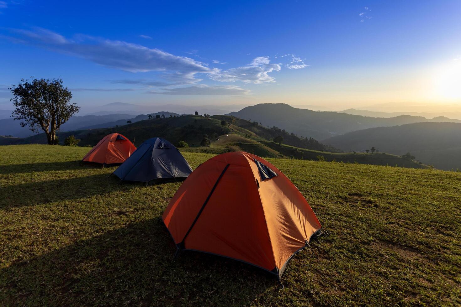 Group of adventurer tent during overnight camping site at beautiful scenic sunset view point of Mae Tho, Chiangmai, Thailand over layer of mountain for outdoor adventure vacation travel photo