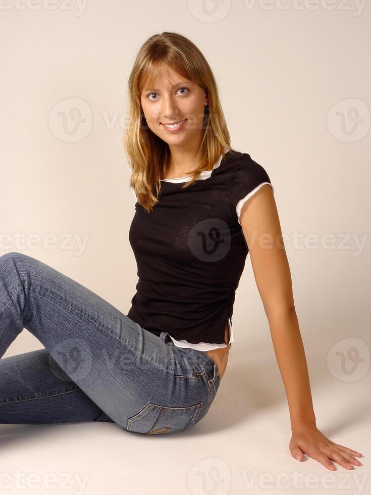joven caucásico rubio mujer sentado en pantalones y parte superior foto