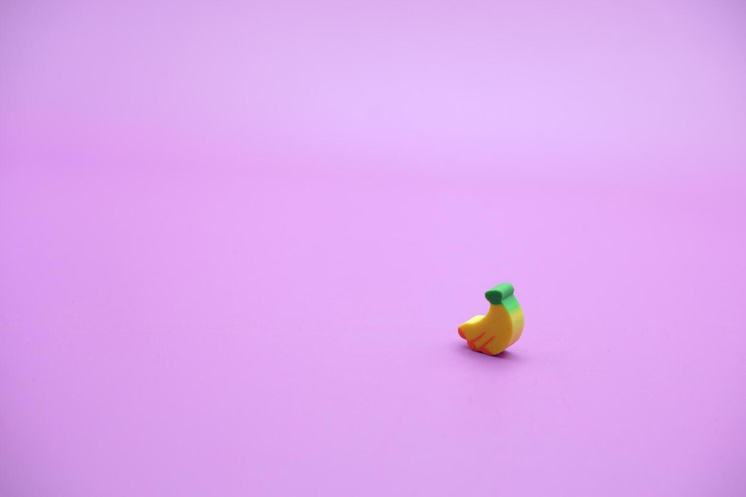 Mini banana toy isolated on purple background. purple background with banana toys. photo