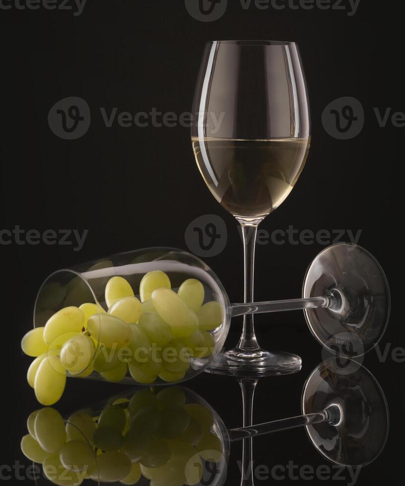 a glass of white wine and grapes on a black background photo