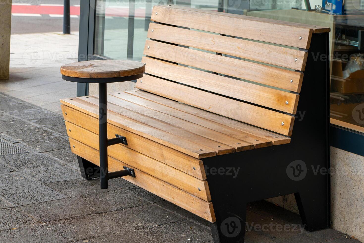 a wooden bench with a small table in a town photo