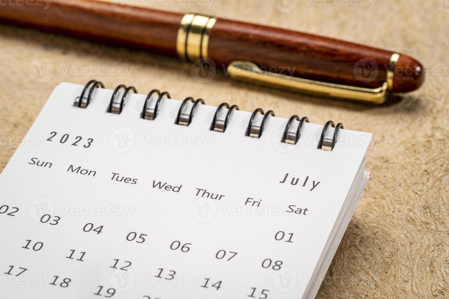 July 2023 - closeup of a small desktop calendar with a pen, time and business concept photo