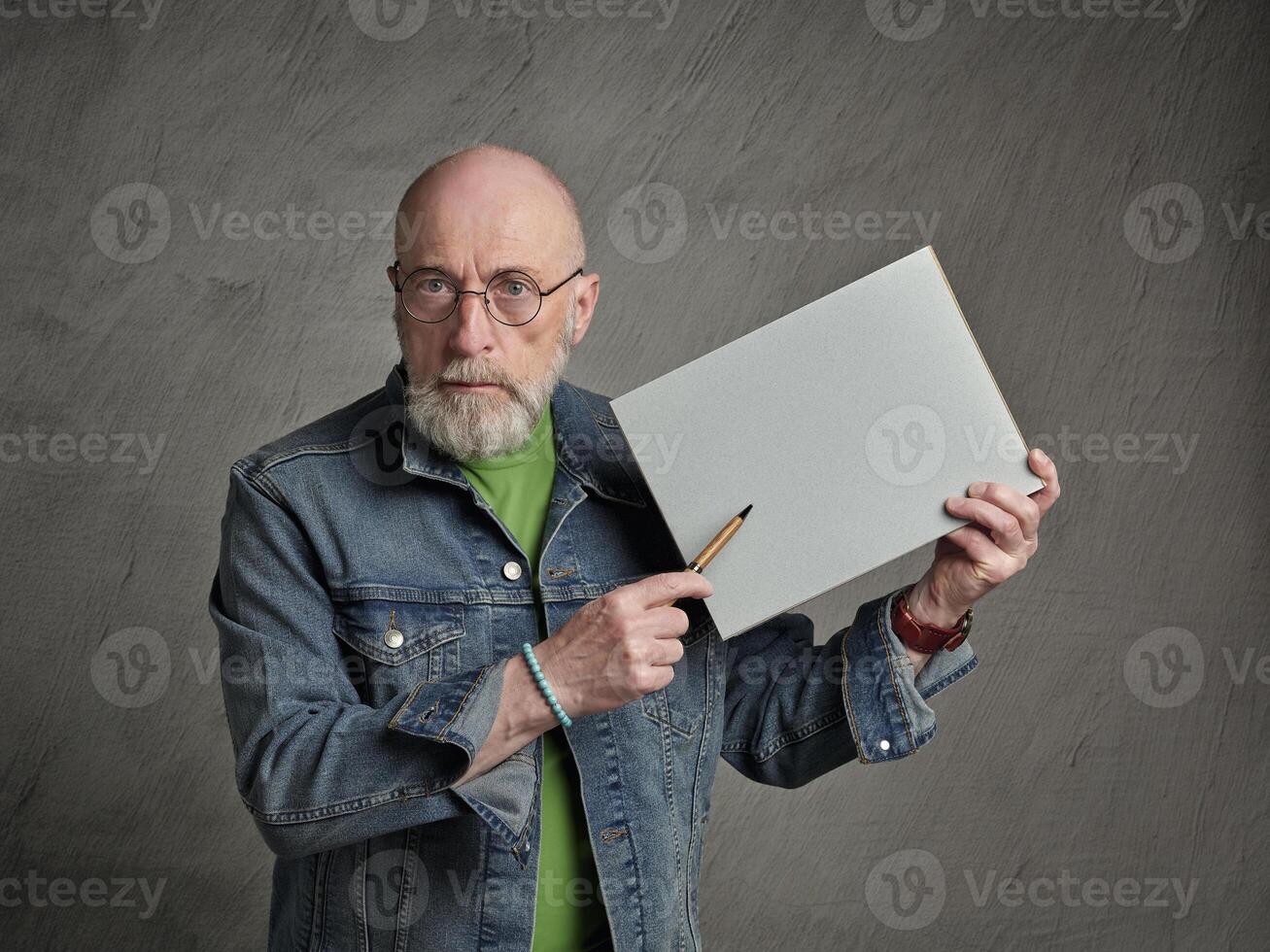 senior man is holding a blank sheet of paper and a pen, presentation concept photo