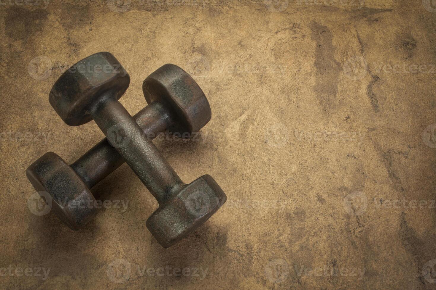 old rusty dumbbells on textured handmade bark paper with a copy space photo