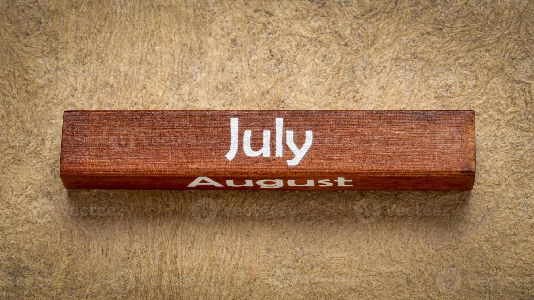 julio y agosto texto en de madera bloquear en contra hecho a mano ladrar papel en tierra tonos, calendario concepto foto